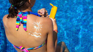 Eine Frau hat Sonnencreme in Form einer Sonne und Wellen auf ihrem Rücken aufgetragen.