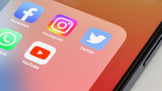 Auf einem Handy-Bildschirm sind App-Symbole von Facebook, Instagram, WhatsApp und YouTube zu sehen.